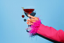 Women Hand Holding Glass With Drunk Cherry Cocktail Over Blue Pop Art Background. Copy Space For Ad.