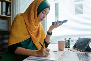 Wall Mural - Muslim UI designer listening to voice message from coworker and correcting interface wireframe