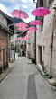 Des parapluies roses en décoration dans une rue piétonne de Chanaz dans le département de la Savoie en France