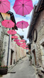 Des parapluies roses en décoration dans une rue piétonne de Chanaz dans le département de la Savoie en France