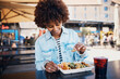 © Flamingo Images - Smiling woman squeezing lime on her tacos on a restaurant patio
