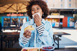 © Flamingo Images - Woman wiping her mouth with a napkin while eating tacos on a restaurant patio