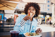 Young Woman Biting Into A Taco Outside On The Patio Of A Restaurant