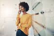 © Flamingo Images - Young businesswoman talking on her phone while leaning against a glass wall