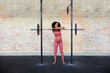 © Flamingo Images - Smiling woman leaning against barbells in a gym