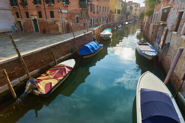 Canvas Print - Boats covered from rain parked in the water next to the house in canal of Venice. Water transport and transportation theme.