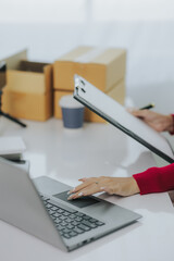 Close up Asian woman wearing red boxed shirt SME small business entrepreneur startup portrait of Asian small business owner in home office, online sales, telemarketing SME ecommerce concept