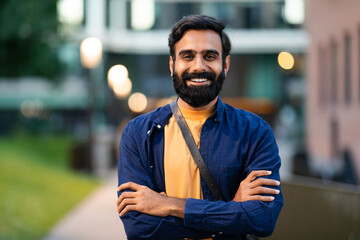 Portrait of cheerful bearded arabic guy posing in urban area