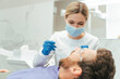 © Maria Vitkovska - Professional beautiful female dentist in protective mask treatment teeth of male patient