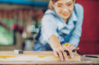 © EKKAPON - Attractive middle aged woman carpenter designer works with ruler, make notches on the tree in workshop. Image of modern femininity. Concept of professionally motivated women
