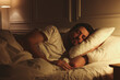 © New Africa - Handsome man sleeping in bed at night
