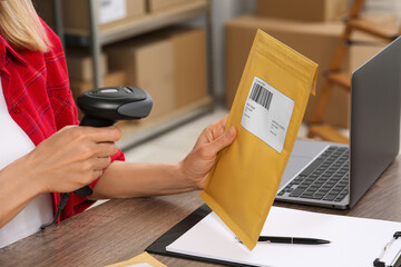 Wall Mural - Seller with scanner reading parcel barcode at table in office, closeup. Online store