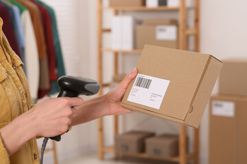 Canvas Print - Seller with scanner reading parcel barcode in office, closeup. Online store