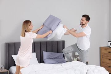 Wall Mural - Couple having pillow fight while changing bed linens at home