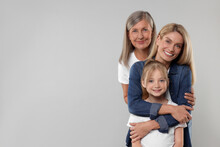 Three Generations. Happy Grandmother, Her Daughter And Granddaughter On Light Gray Background, Space For Text