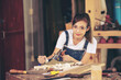 © EKKAPON - Young Female Artisan Carpenter Using Hand Plane to Shape a Wood Bar. Beautiful Artist Working on a Project in a Woodworking Workshop.