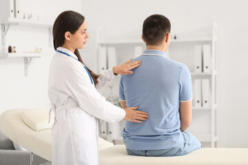 Poster - Female doctor checking posture of young man in clinic