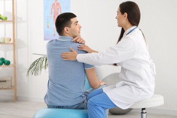 Poster - Female doctor checking posture of young man in clinic