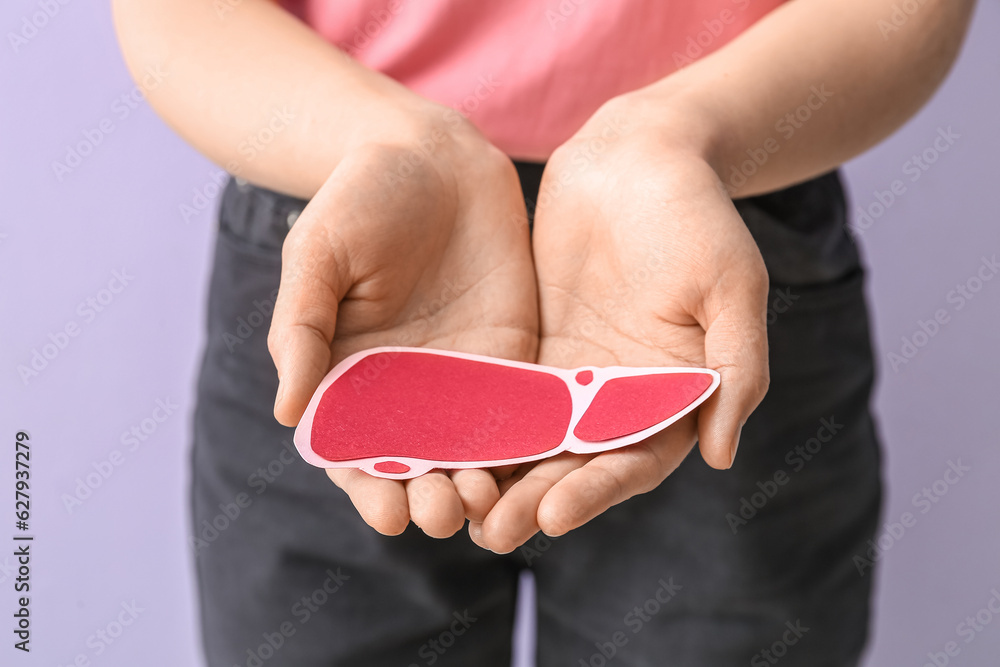 Woman holding red paper liver on lilac background