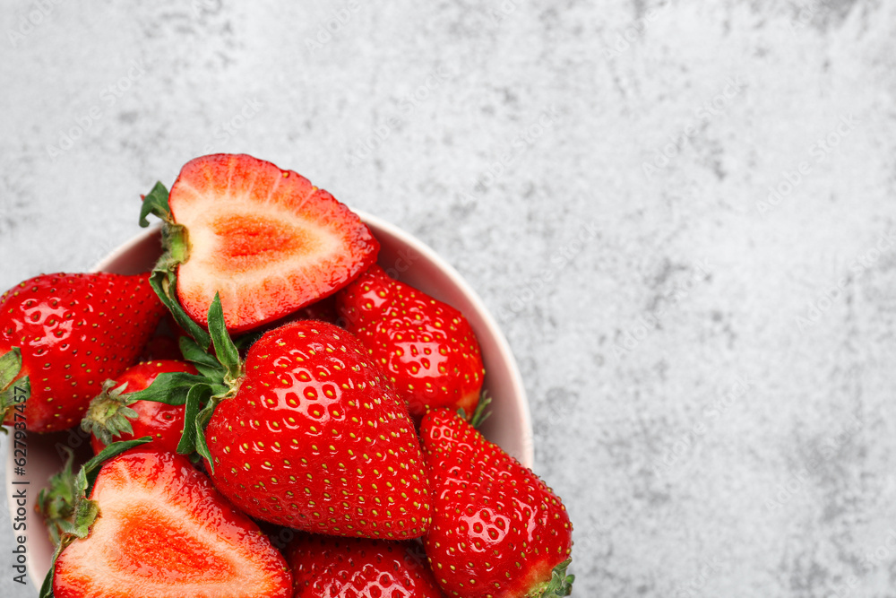 Bowl of fresh strawberries on grey grunge background
