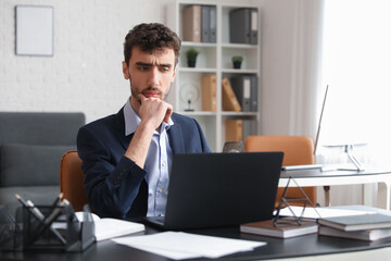 Sticker - Thoughtful young businessman working with laptop at table in office