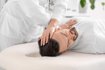 Wall Mural - Female physiotherapist working with young man on couch in rehabilitation center, closeup