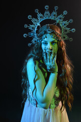 Wall Mural - portrait of beautiful brunette woman wearing ornate silver crown headdress, posing with arm gestures, conjuring  magical spell. isolated on dark studio background, cinematic blue moonlight lighting.