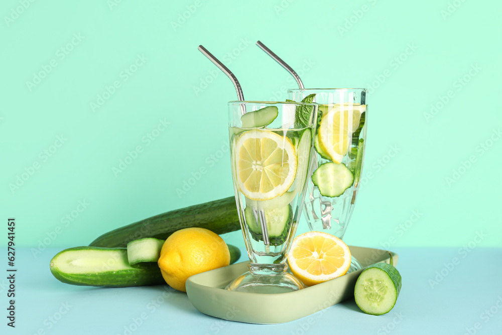 Glasses of lemonade with cucumber and mint on blue background