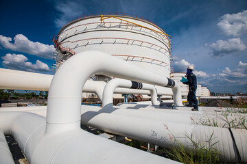 Wall Mural - Male worker inspection at steel long pipes and pipe elbow in tank oil station oil factory during refinery valve of visual check record pipeline oil and gas