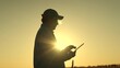 © SUPER FOX - Embracing golden breathtaking sunset, modern farmer harnesses power digital technologies revolutionize agriculture. Witness silhouette dedicated agronomist work wonders field, using tablet optimize