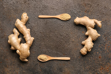 Frame made of fresh ginger roots and wooden spoons with dried powder on dark background