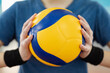 Close up of volleyball ball in hands of female player. Ball of yellow and blue colours, practice, physical training