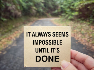 Wall Mural - Motivational and inspirational wording. It Always Seems Impossible Until It’s Done written on a notepad. With blurred styled background.