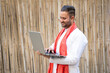 indian man in traditional wear and using laptop