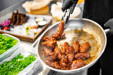 Wall Mural - chef cooking chicken wings in a sauce in the kitchen