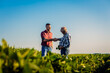 Two farmers in soy field making agreement with handshake.