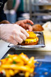 © pavel siamionov - chef hand cooking burger with vegetables and meat on restaurant kitchen