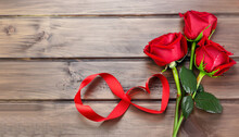 Red Roses And Heart Shape Ribbon Over Wooden Table. Valentines Day Background. Top View With Copy Space