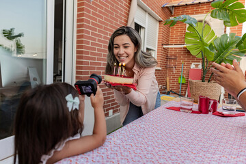 Wall Mural - mother with cake with candles celebrating birthday with her little daughter