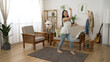 © PRPicturesProduction - hyped Asian young woman is dancing funny moves and ending with a pose in a modern home living room interior with daylight.