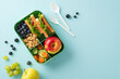 An appealing and health-conscious school lunch scene captured from above. The lunchbox features delectable sandwiches and fresh snacks on a blue background, offering copyspace for text or advertising