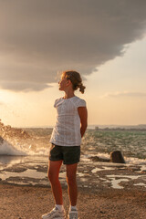 a girl stands on the shore of a troubled sea before the rain. relax and enjoy the sound of the surf