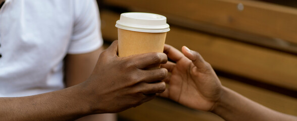 close up person's hand giving a coffee to a friend, taking care