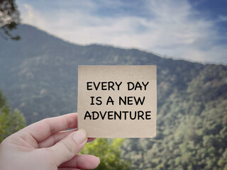 Wall Mural - Motivational and inspirational wording. Every Day Is A New Adventure written on a paper. With blurred styled background.