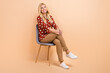 Full body cadre of young woman sitting comfortable armchair dreaming psychotherapy session look novelty isolated on beige color background