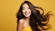 portrait studio shot of an asian female model with long black hair smiling for the camera with orange yellow theme