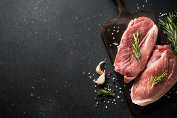 Wall Mural - Raw meat steaks with spices at dark background. Top view with space for text.