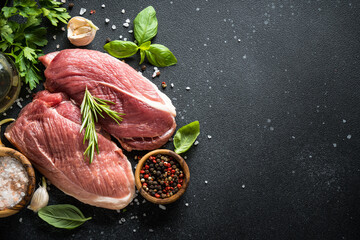 Wall Mural - Raw meat steaks with spices, herbs and oil at dark background. Top view with space for text.