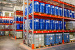 Storehouse with barrels. Interior storage area of enterprise. Blue barrels on pallets. Multi-tier warehouse racks. Storehouse in industrial hangar. Place to store finished products in manufactory