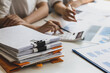 © Wasan - Colleagues work on paperwork on their desks. Businesswoman discussing business project project documents in office.